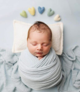 Baby wrapped in blue and lying with props for studio shoot at Heather Nicole Photography in Redondo Beach, Ca.