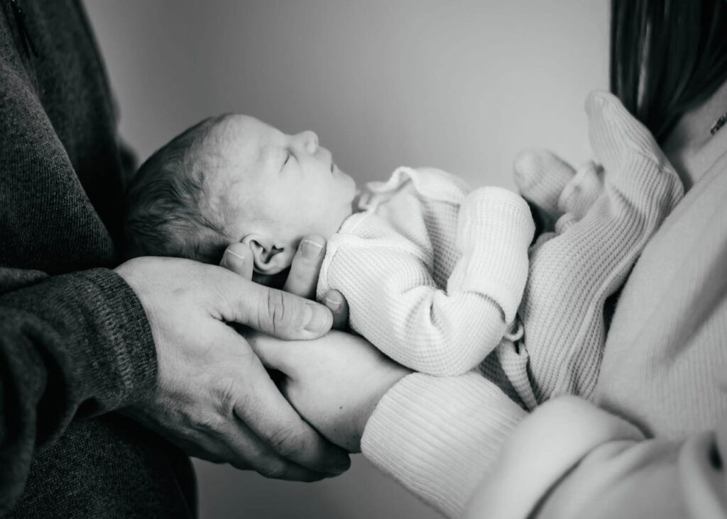Newborn baby being held in parents hands during photo session at Heather Nicole Photography studio in Redondo Beach.