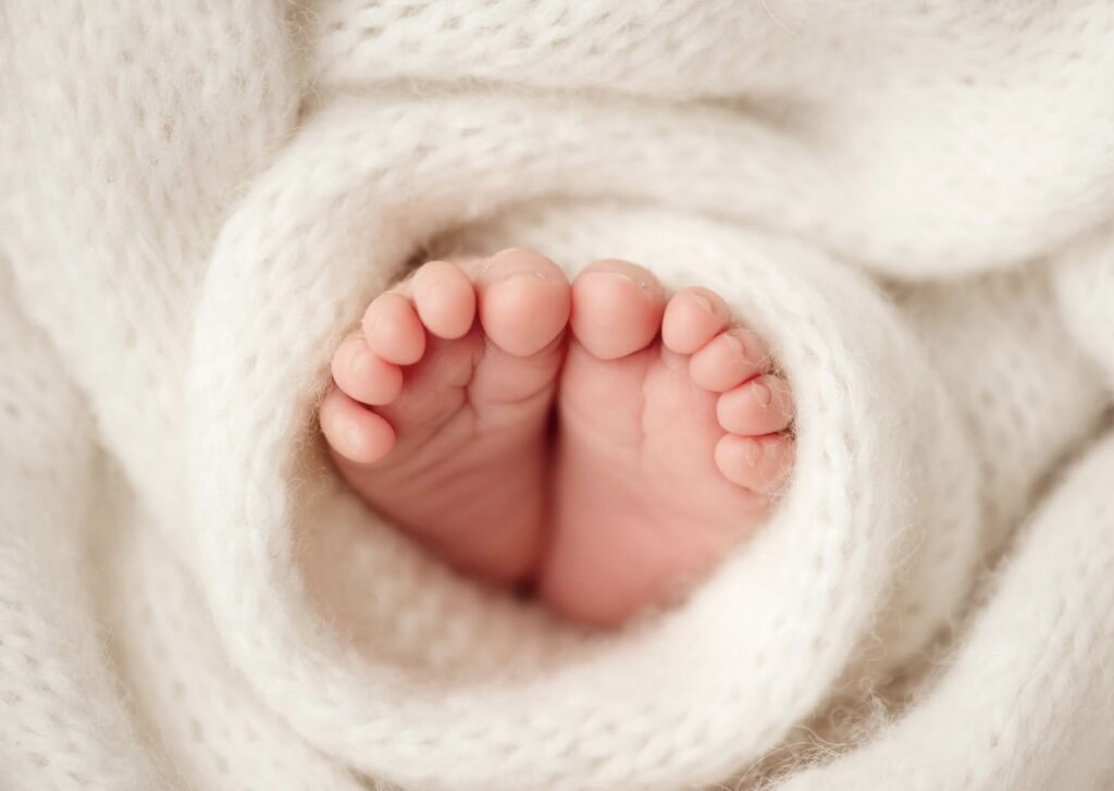 Infant feet wrapped in a soft, cream blanket during newborn photoshoot at Heather Nicole photography Studio.