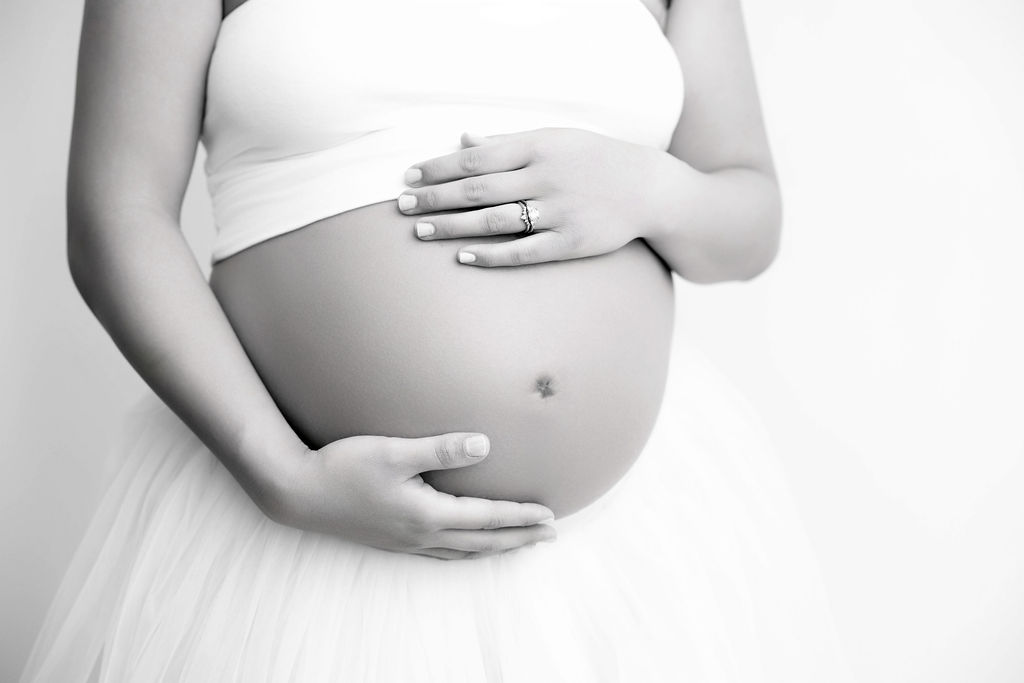Details of a mother to be's bump with her hands on it