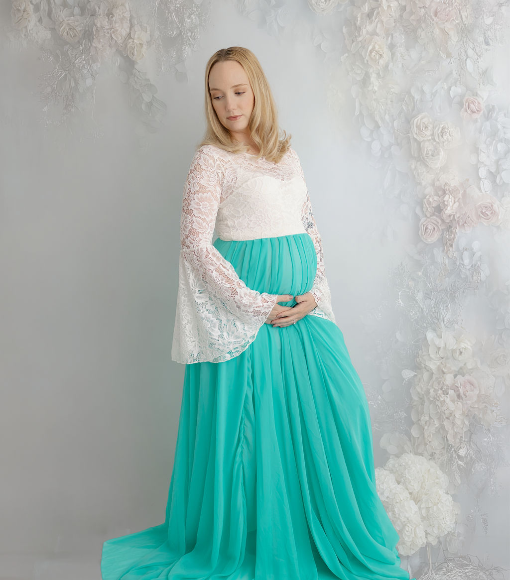 A mother to be in a lace and chenille maternity gown in a studio gazing down her shoulder after some prenatal yoga in redondo beach