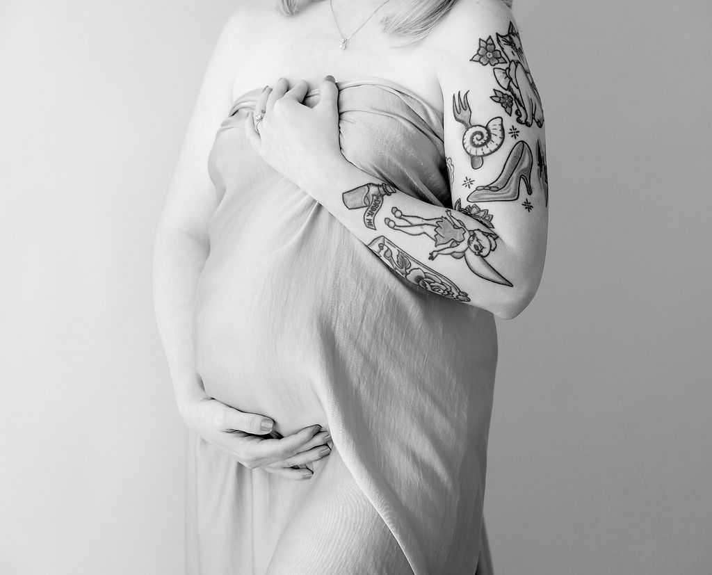 Details of a pregnant woman's bump under a silk sheet wrapped around her