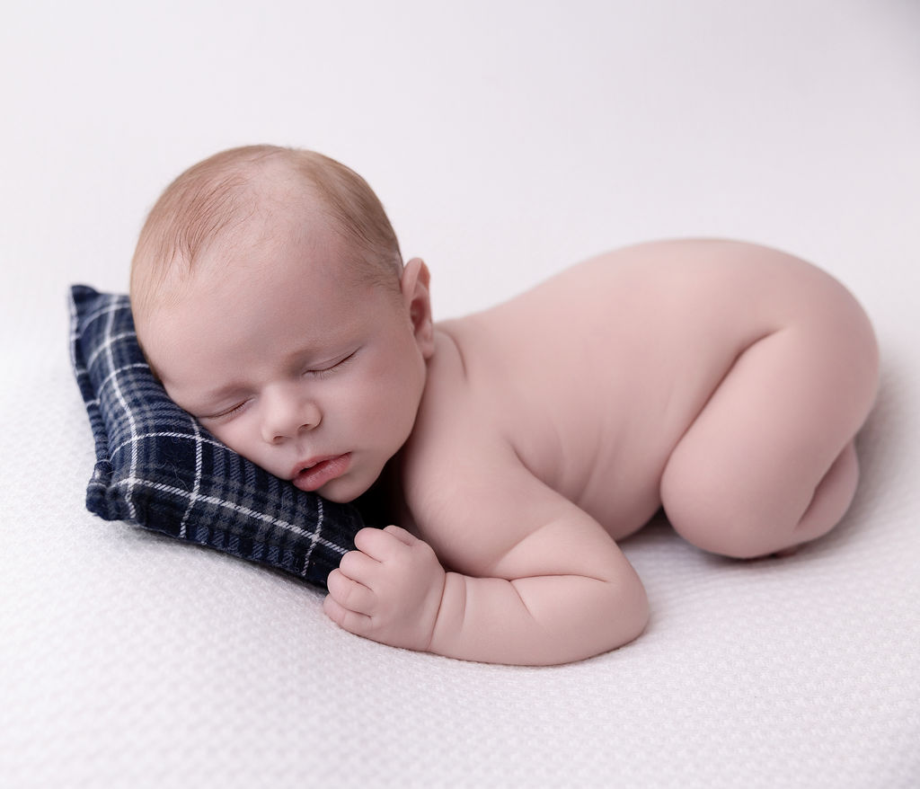 A newborn baby sleeps on tummy naked on a pillow after meeting pediatricians in torrance