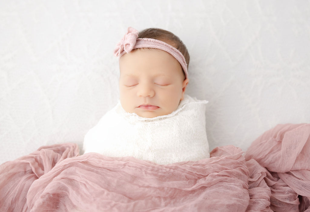 A sleeping newborn baby girl under a pink blanket in a studio after meeting postpartum doulas in torrance