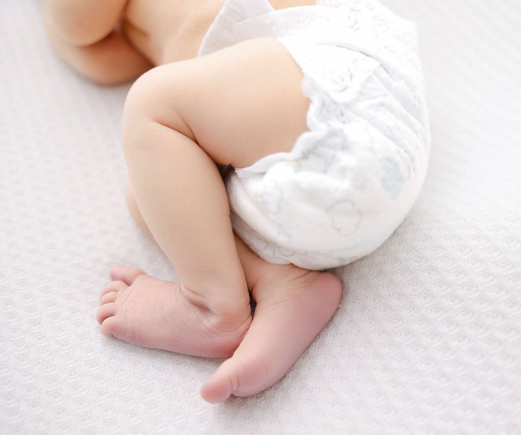 Details of a newborn baby's legs and feet on a bed in a diaper after visiting pediatric chiropractors in torrance
