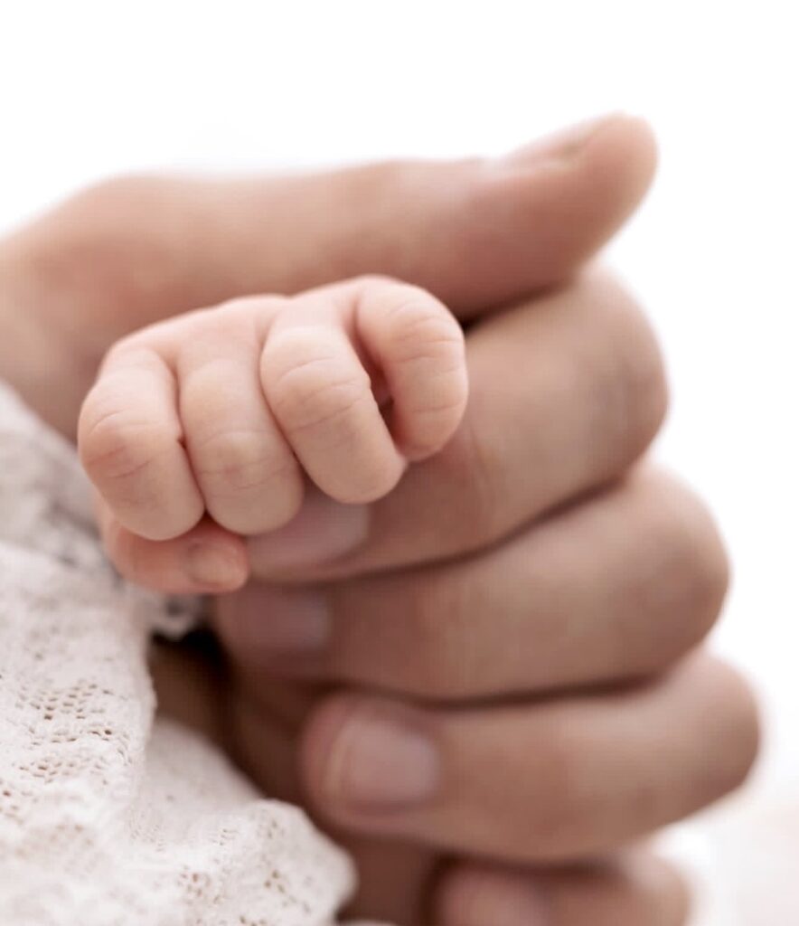Father holding his newborn baby's hand for a close-up image at Heather Nicole photography Studio